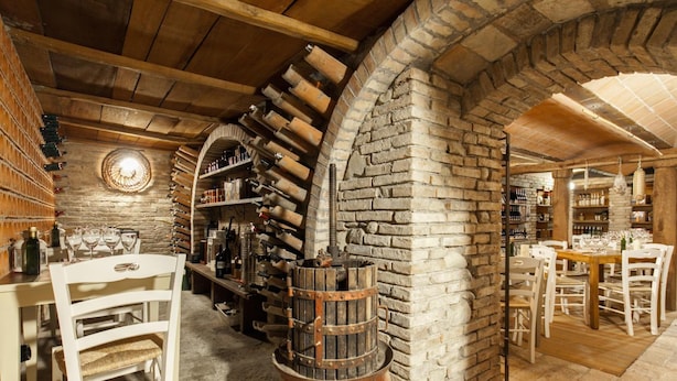 A rustic cellar with wooden shelves, a barrel, and a stone wall. - Locanda Antiche Macine (Santarcangelo di Romagna)