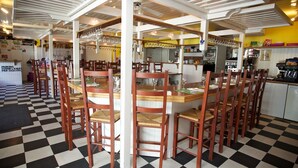Een restaurant met geruit vloerbedekking, houten stoelen en een grote eettafel in het midden.