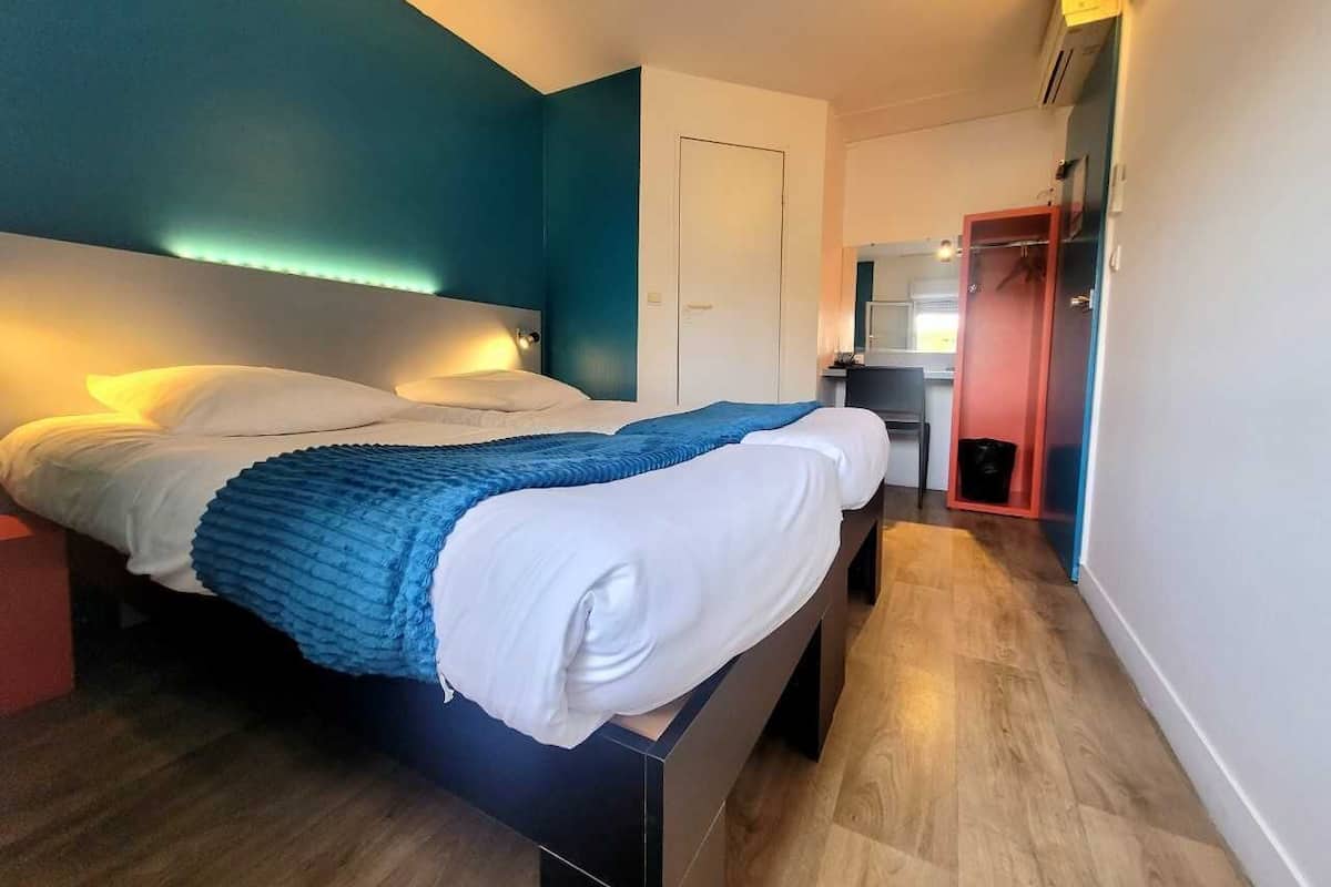 Una habitación de hotel moderna con cama, mesitas de noche y una kitchenette.