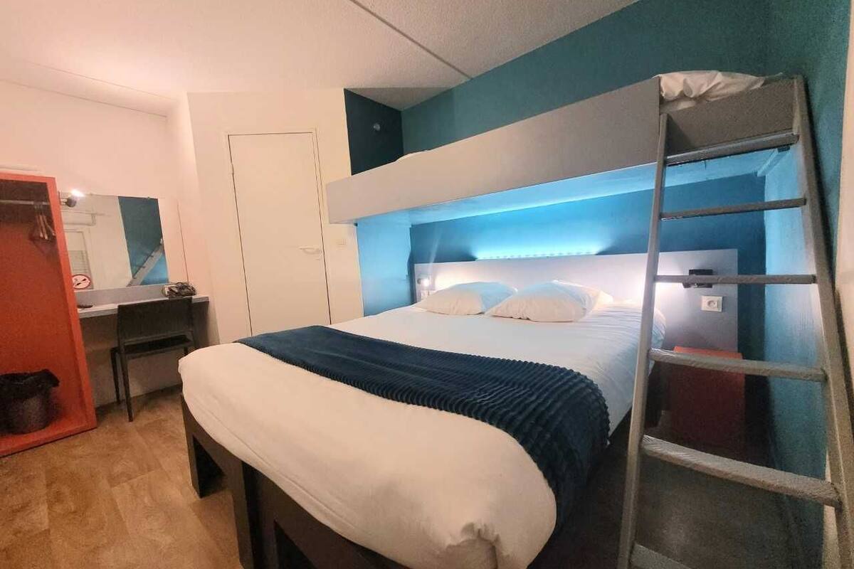 Un dormitorio con literas, un escritorio, una silla y una escalera.