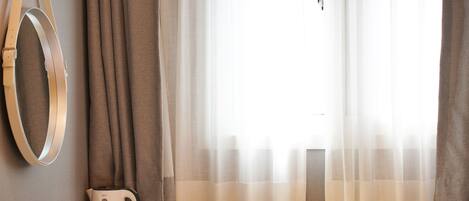 A hotel room with a wooden desk, a coffee maker, and a mirror on the wall.