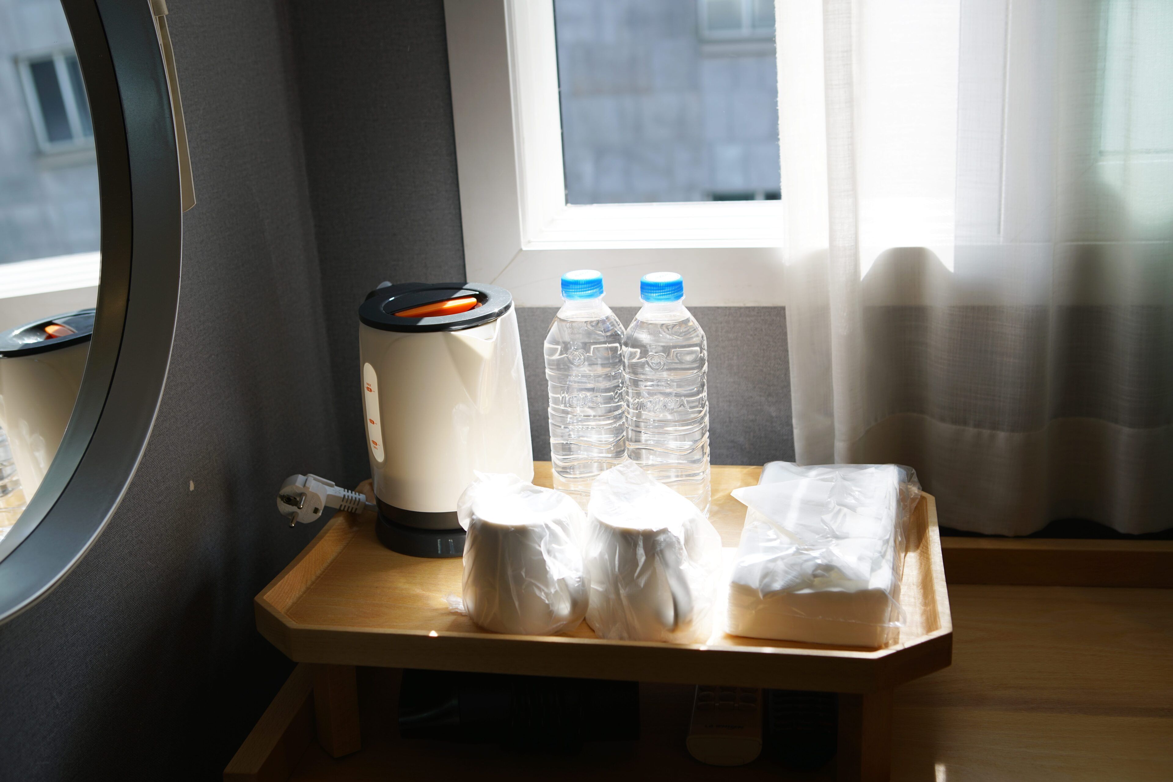 A small wooden table with a coffee maker, two water bottles, and some wrapped items.