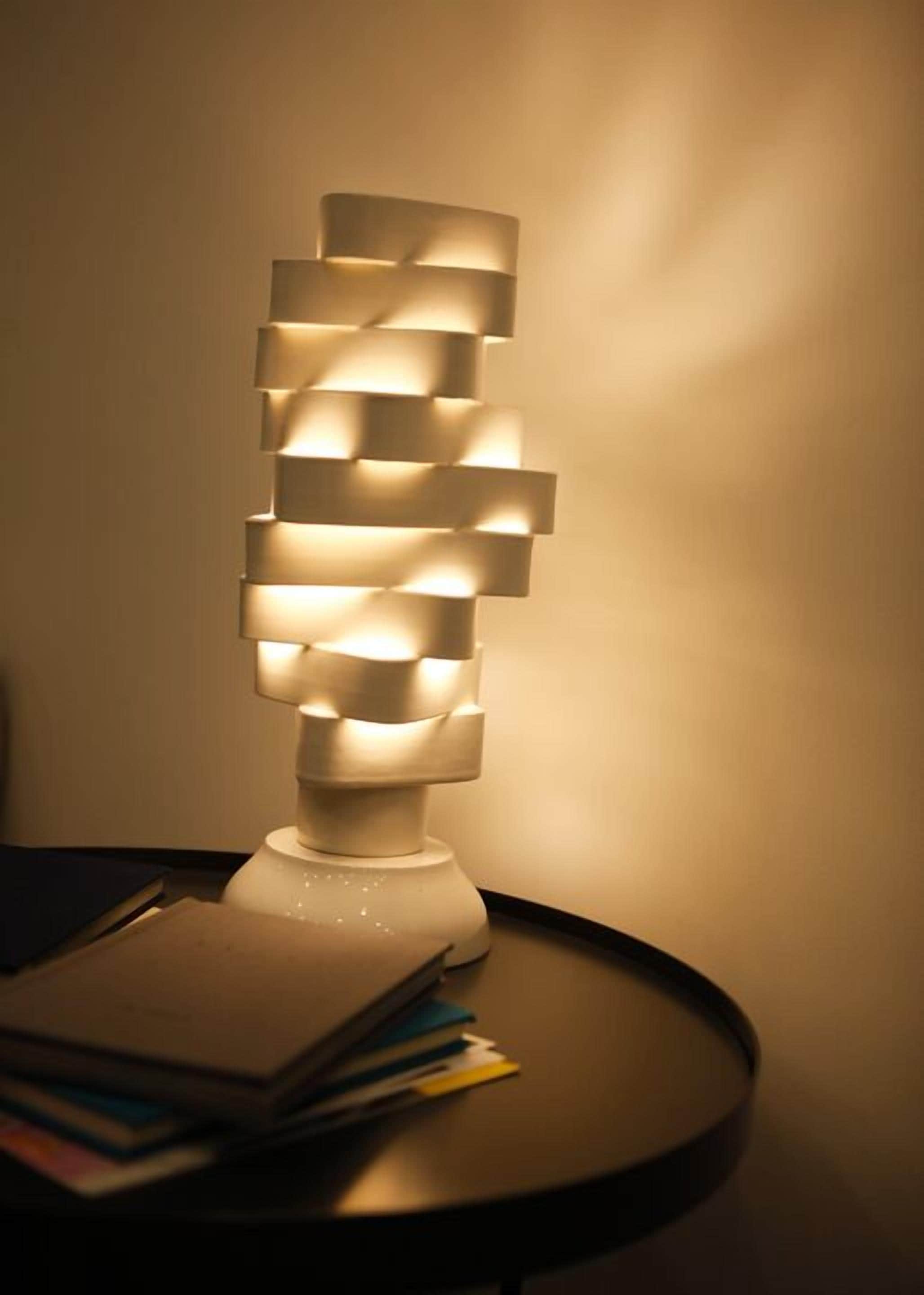 A modern, geometric lamp with multiple rectangular shades on a round table.
