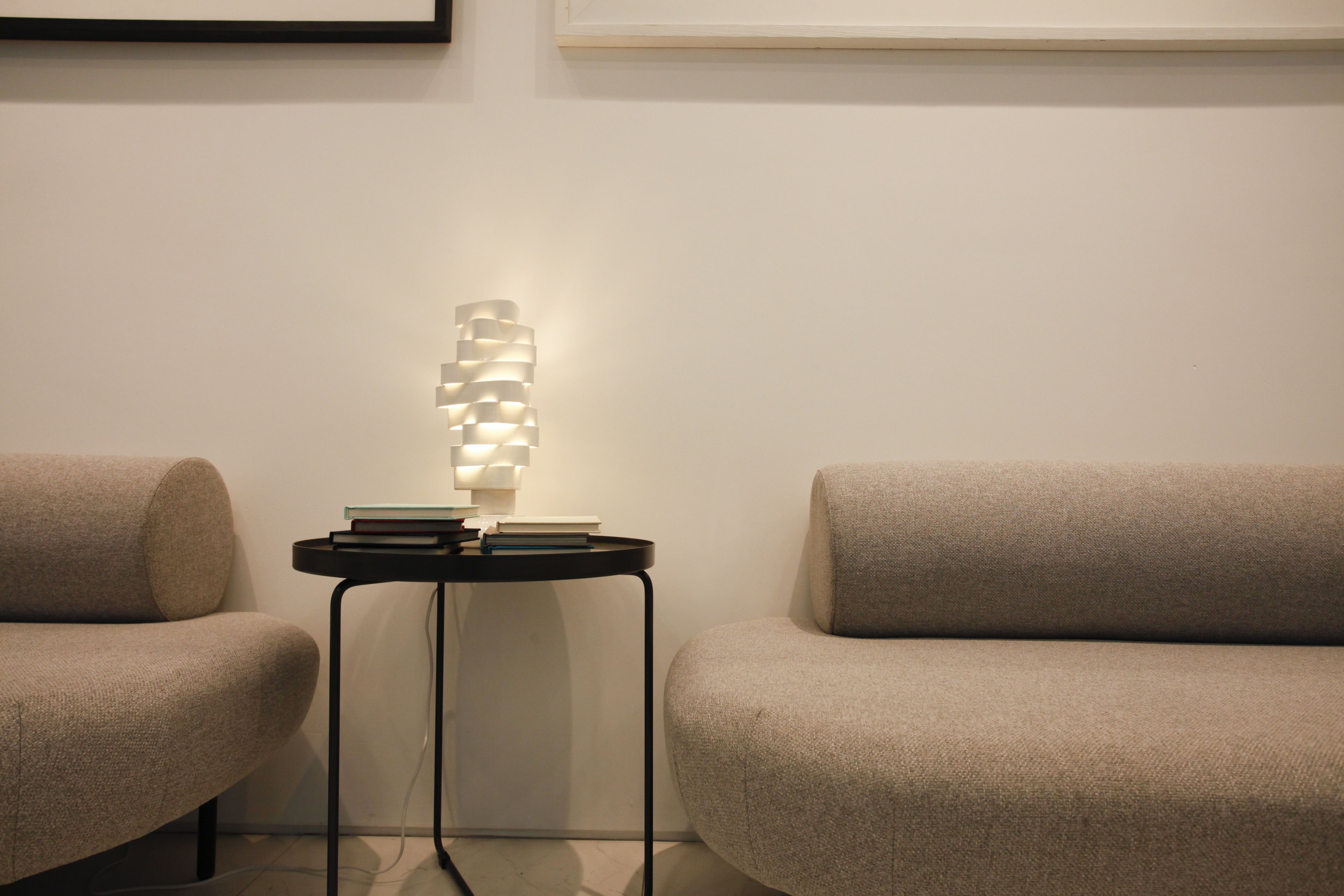 Una sala de estar moderna con un sofá, una mesita de noche con libros y una lámpara original.