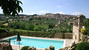 Una piscina con vistas a un pueblo histórico al fondo.