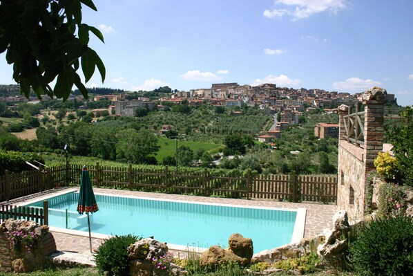 A swimming pool with a view of a historic town in the background. - Agriturismo La Pietriccia (Chianciano Terme)