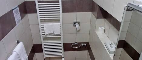 A small bathroom with a toilet, bidet, towel rack, and a paper towel dispenser.