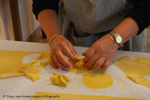 A person preparing food, specifically rolling dough on a table. - Agriturismo La Pietriccia (Chianciano Terme)