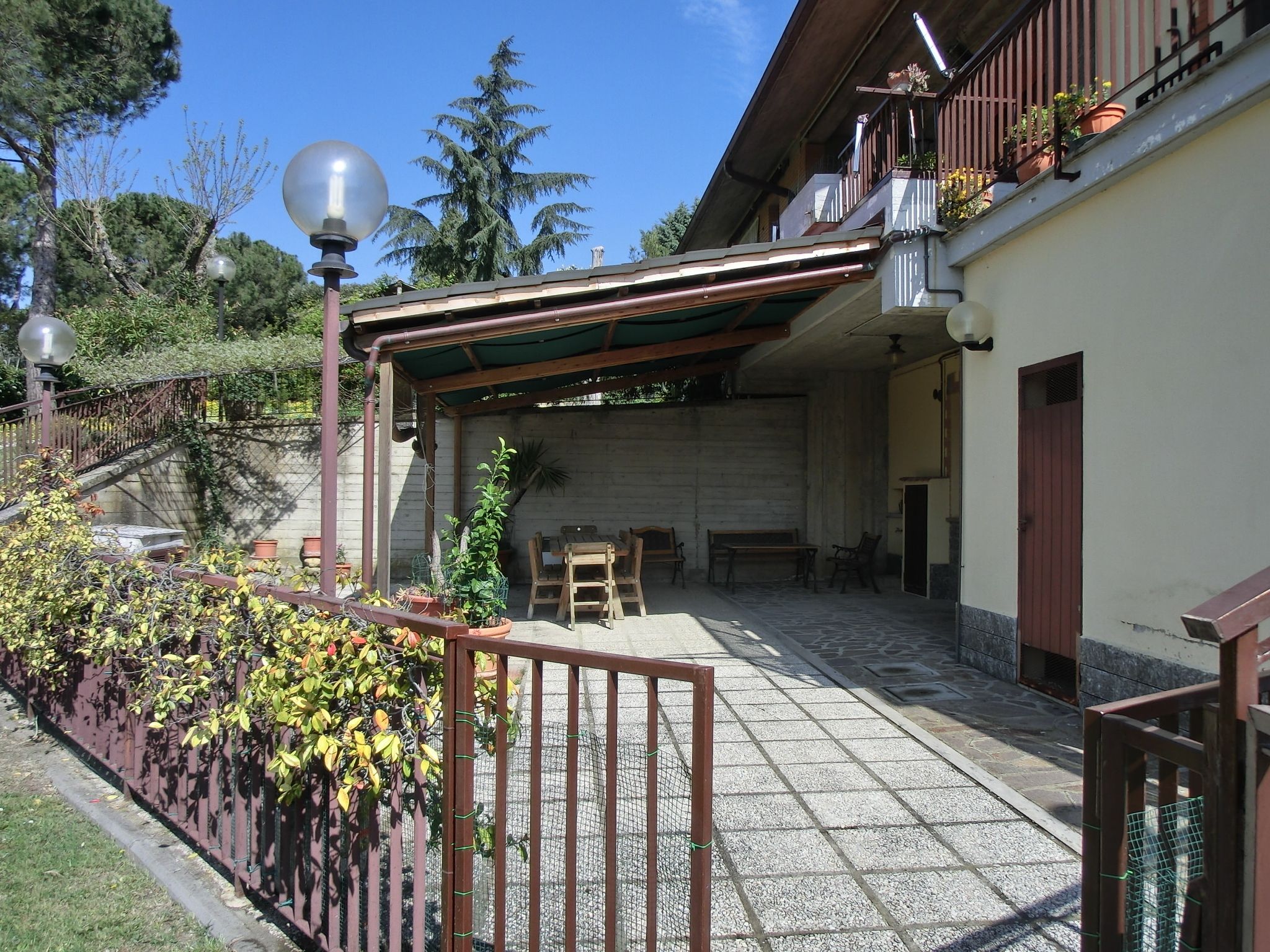 A covered outdoor area with a pergola, seating, and potted plants.