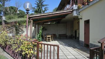 A covered outdoor area with a pergola, seating, and potted plants.
