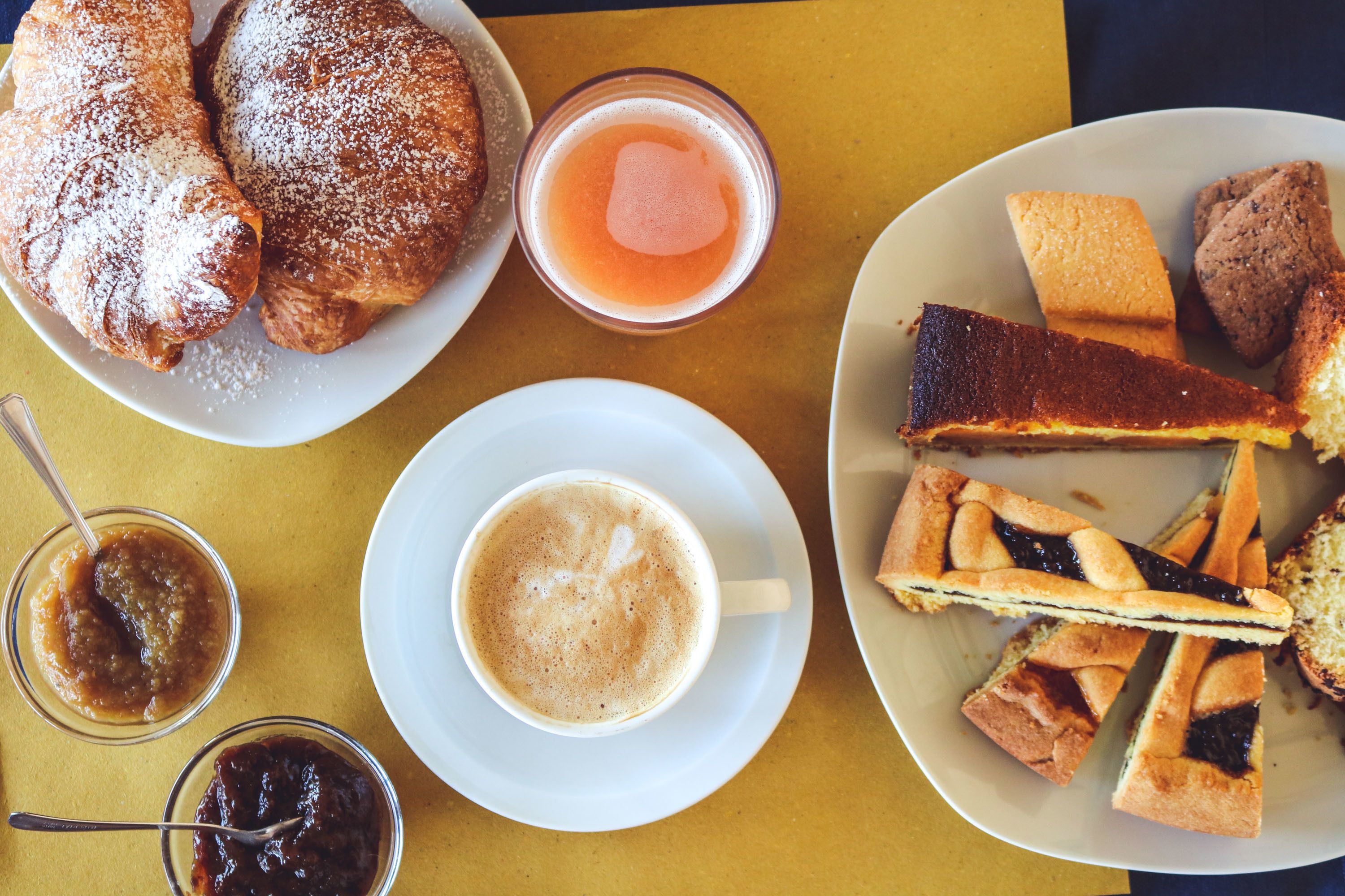 Una mesa con pasteles, un vaso de jugo y una taza de café.