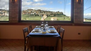 Mesa lista para dos con vista a un pueblo en la ladera, a través de un ventanal amplio.