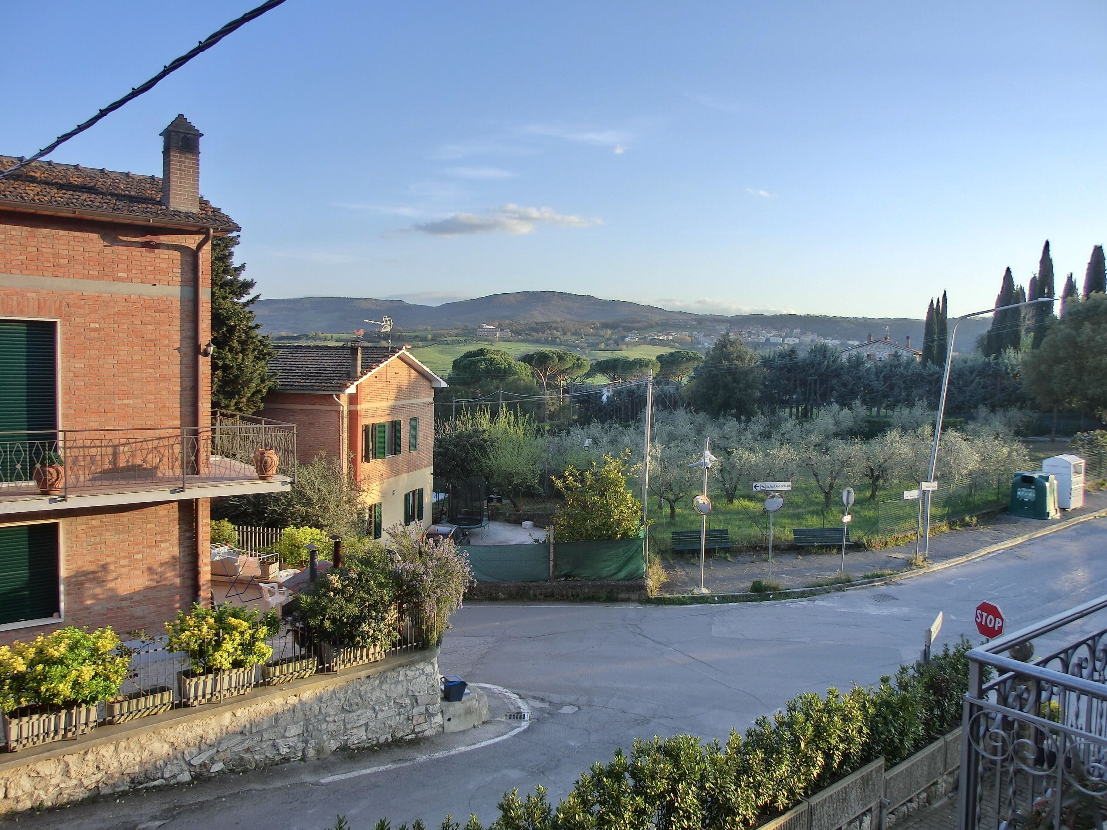 A residential area with a brick house, a balcony, and a street with a stop sign.