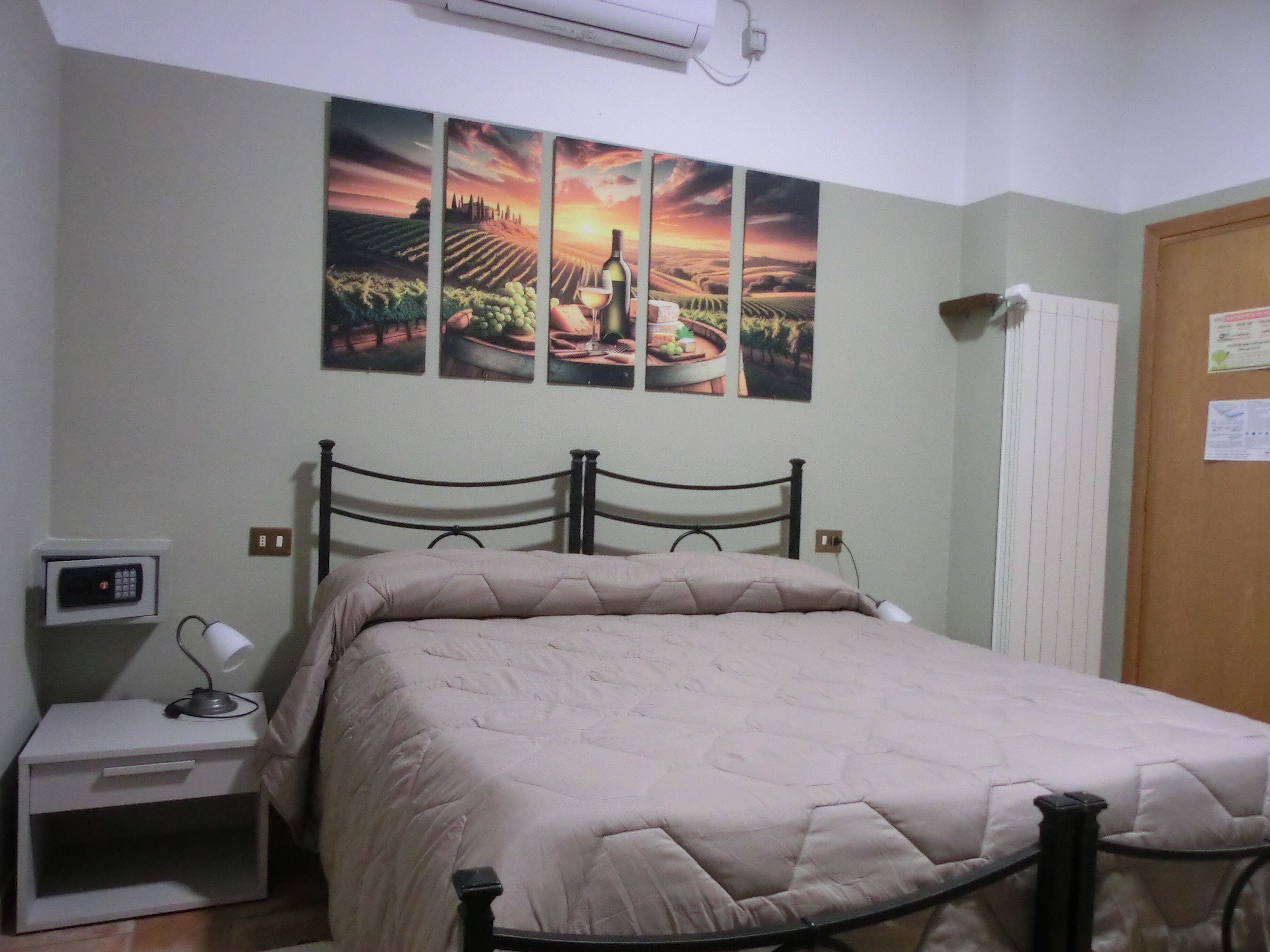 A bedroom with a bed, a nightstand, a wall-mounted air conditioner, and a door with a notice.