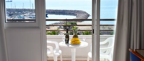 A balcony with a table, chairs, a bottle, and a pineapple.