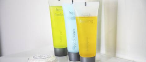 Three bottles of bath gel and a bar of soap on a white surface.