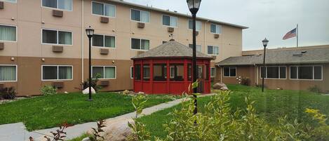 A multi-story building with a red gazebo, air conditioning units, and an American flag.