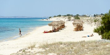 Una playa cerca, sillas reclinables de playa, sombrillas