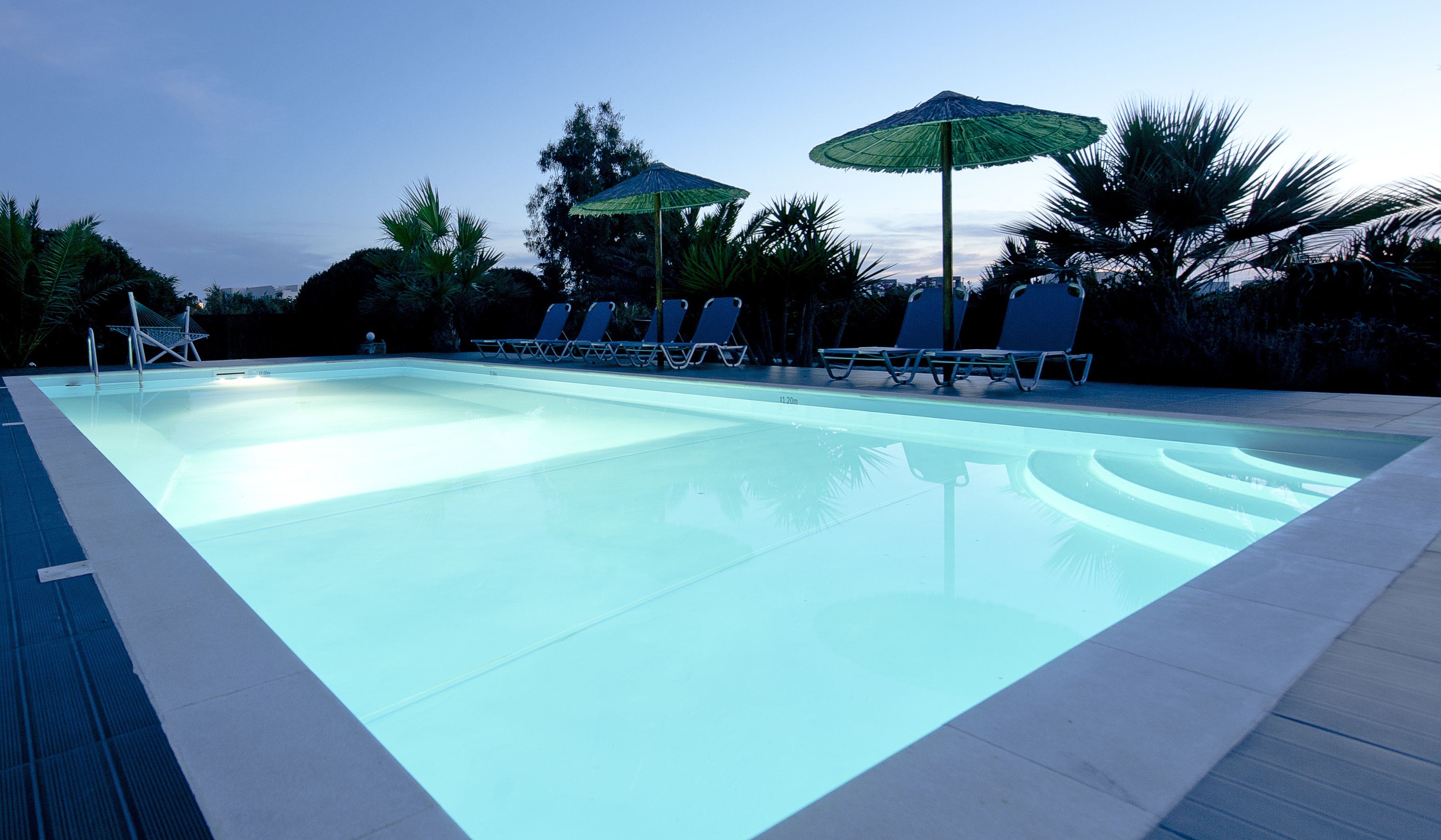 Une piscine avec des chaises longues et des parasols.