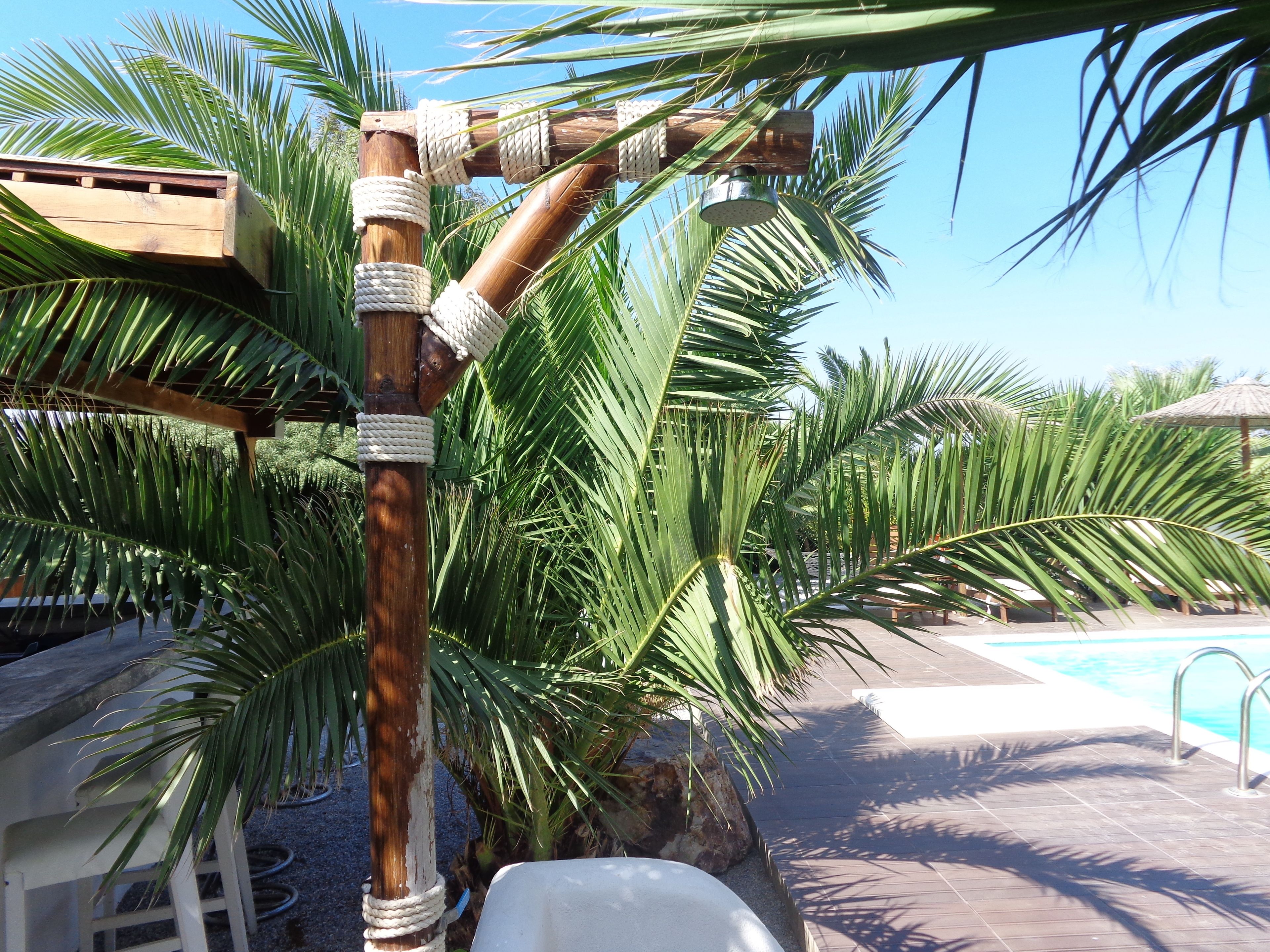 Una estructura de madera con cuerdas, rodeada de palmeras y una zona de piscina.