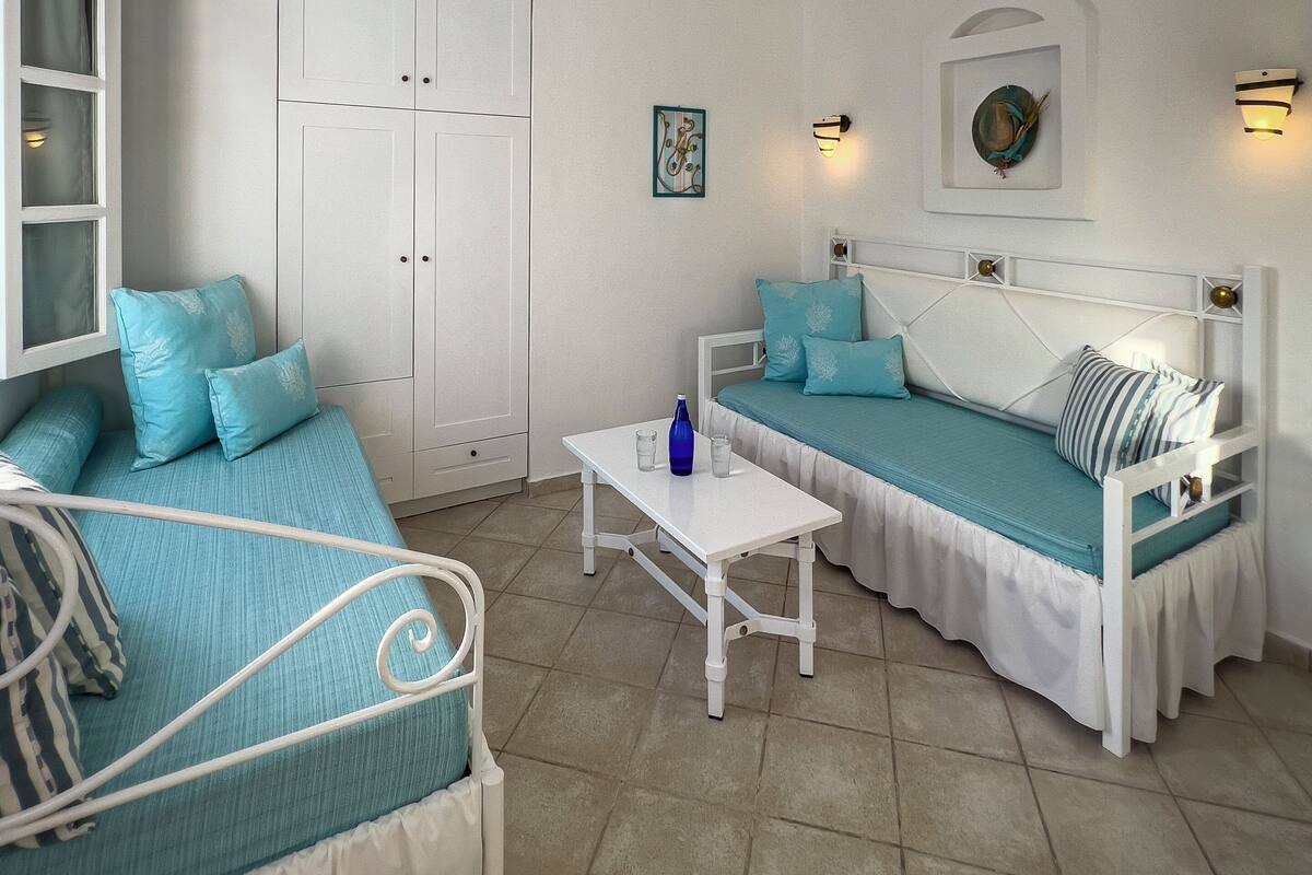 A room with two beds, a white wardrobe, and a small table.