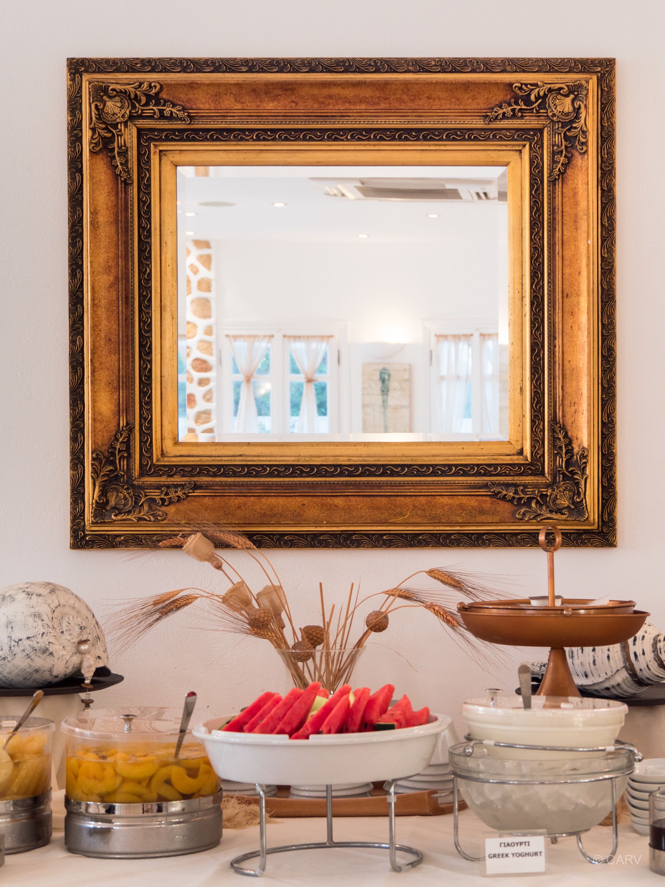 Un buffet garni de divers plats, un miroir décoratif et une œuvre d’art encadrée accrochée au mur.