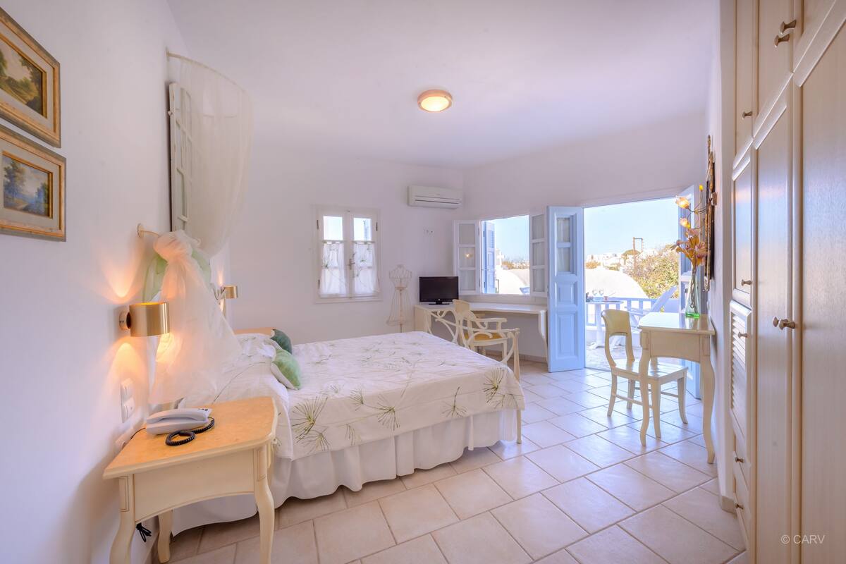 A bedroom with a bed, bedside table, lamp, and a view of the outside balcony.