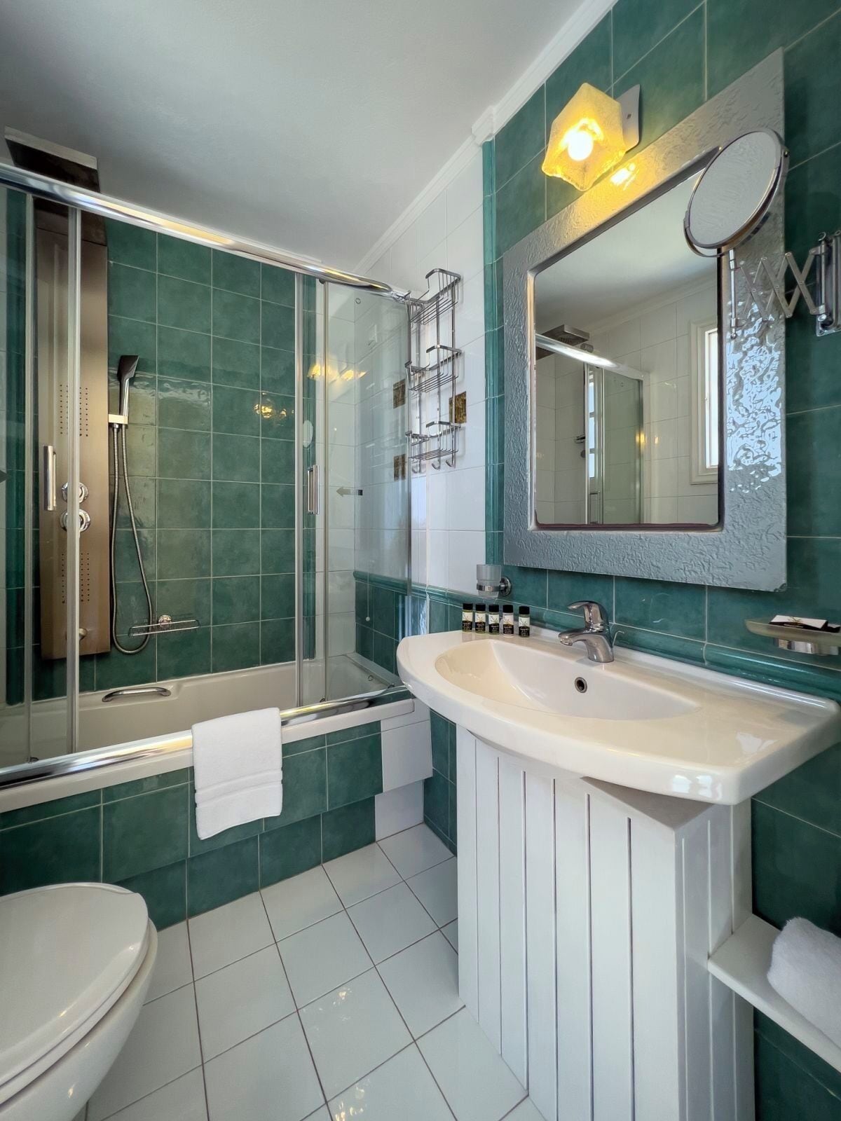 A modern bathroom with a glass-enclosed shower, a white sink, and a large mirror.