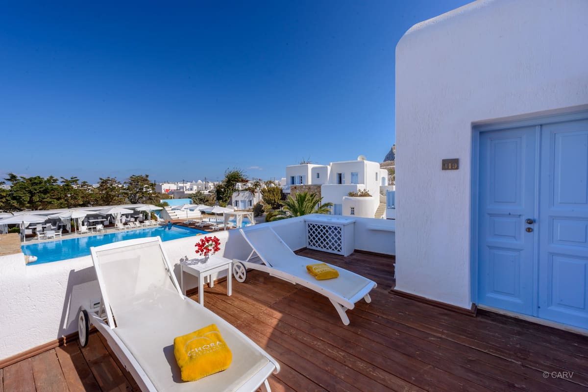 A rooftop pool area with lounge chairs and a door.