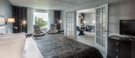 Una habitación de hotel con una cama grande, dos sillones, un escritorio y un televisor.