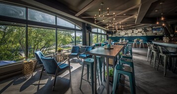 Un restaurante moderno con ventanas amplias, asientos azules y una pared de piedra.