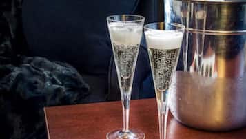 A table with two champagne flutes, a bucket of champagne, and a plate of chocolate-covered strawberries.