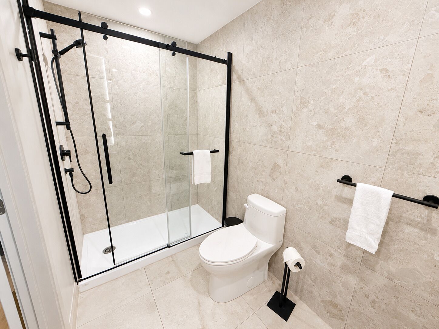 Ein modernes Badezimmer mit einer Glaskabine zur Dusche, einer Toilette und einem Handtuchhalter.