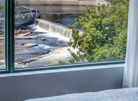 Vista de una cascada a través de una ventana, con una estructura de concreto y vegetación al fondo.