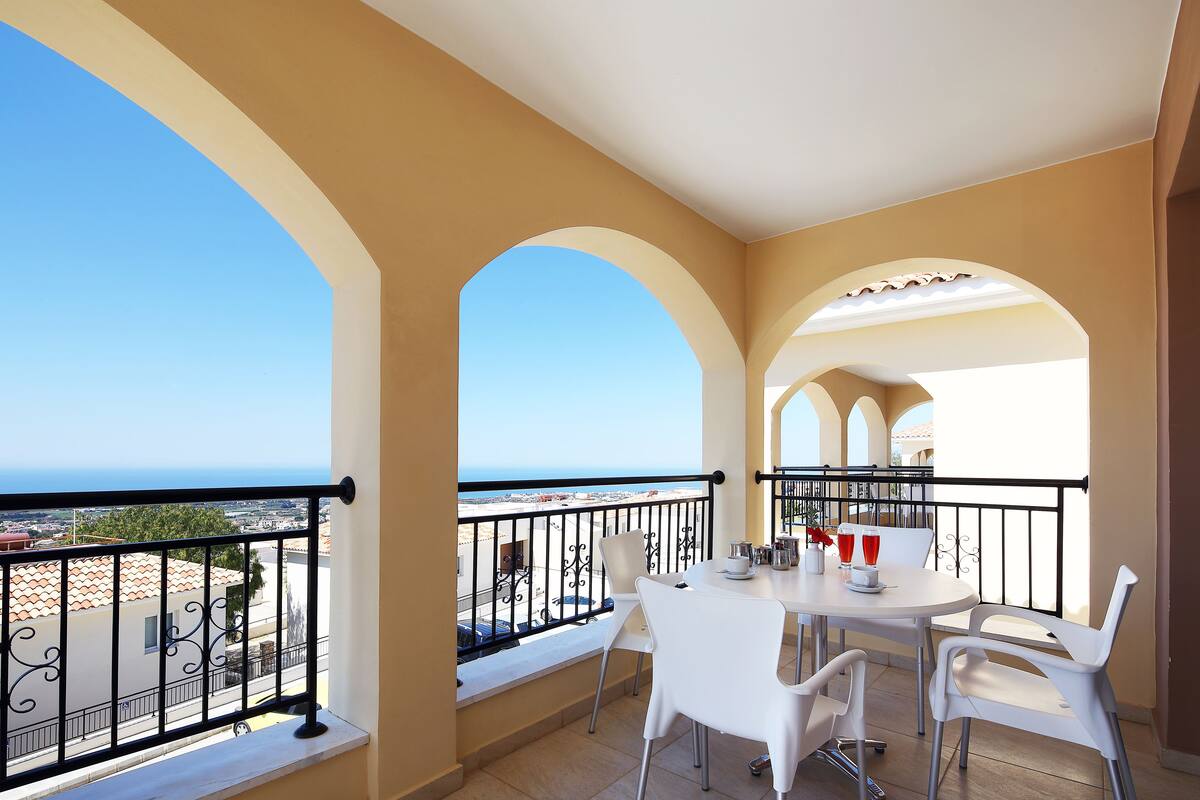 A balcony with a table and chairs, a view of the sea, and a railing.