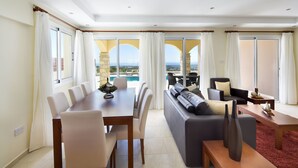 Una habitació d'hotel moderna amb zona de menjador, un sofà i vista al mar.