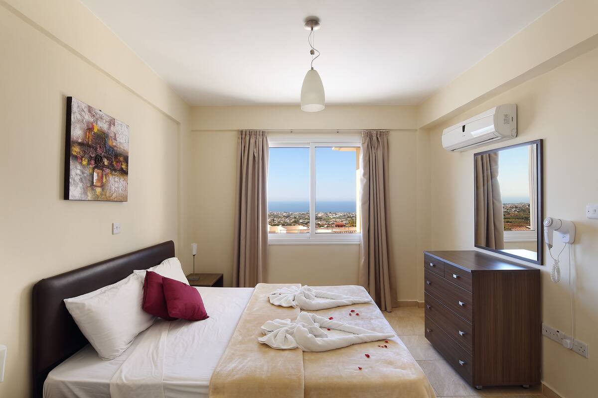 A hotel room with a bed, a dresser, a mirror, and a painting on the wall.