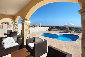 A rooftop pool area with wicker furniture and a clear view of the city skyline.