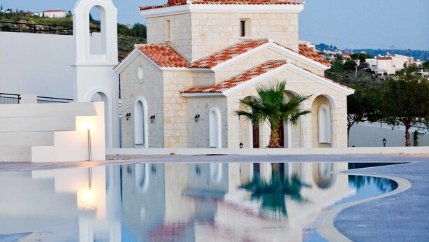 Una església amb una cúpula vermella i un campanar, situada al costat d'una piscina que reflecteix.