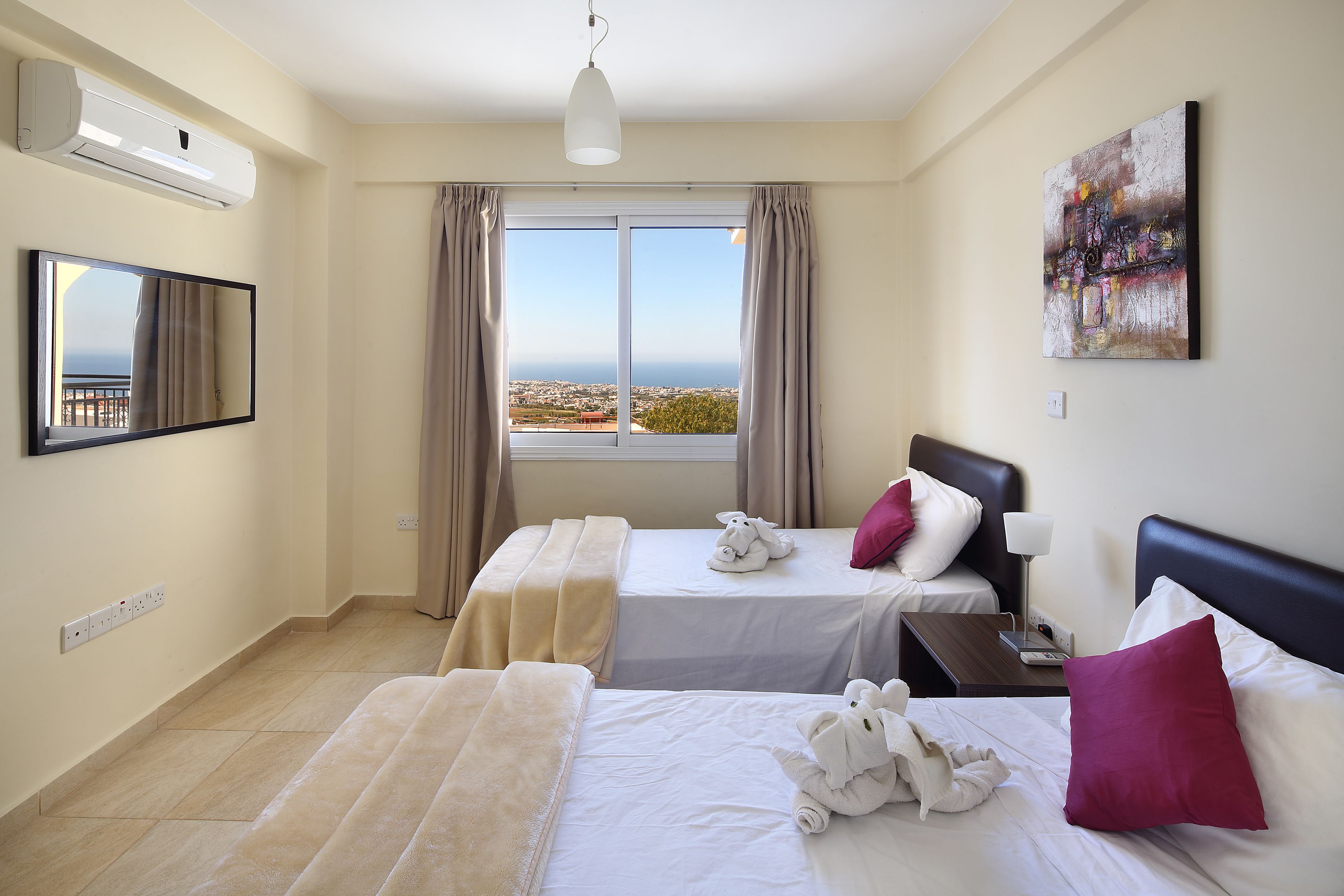 Habitación de hotel con dos camas, un ventanal grande con vista a la ciudad, una obra de arte colgada en la pared y un televisor de pantalla plana.