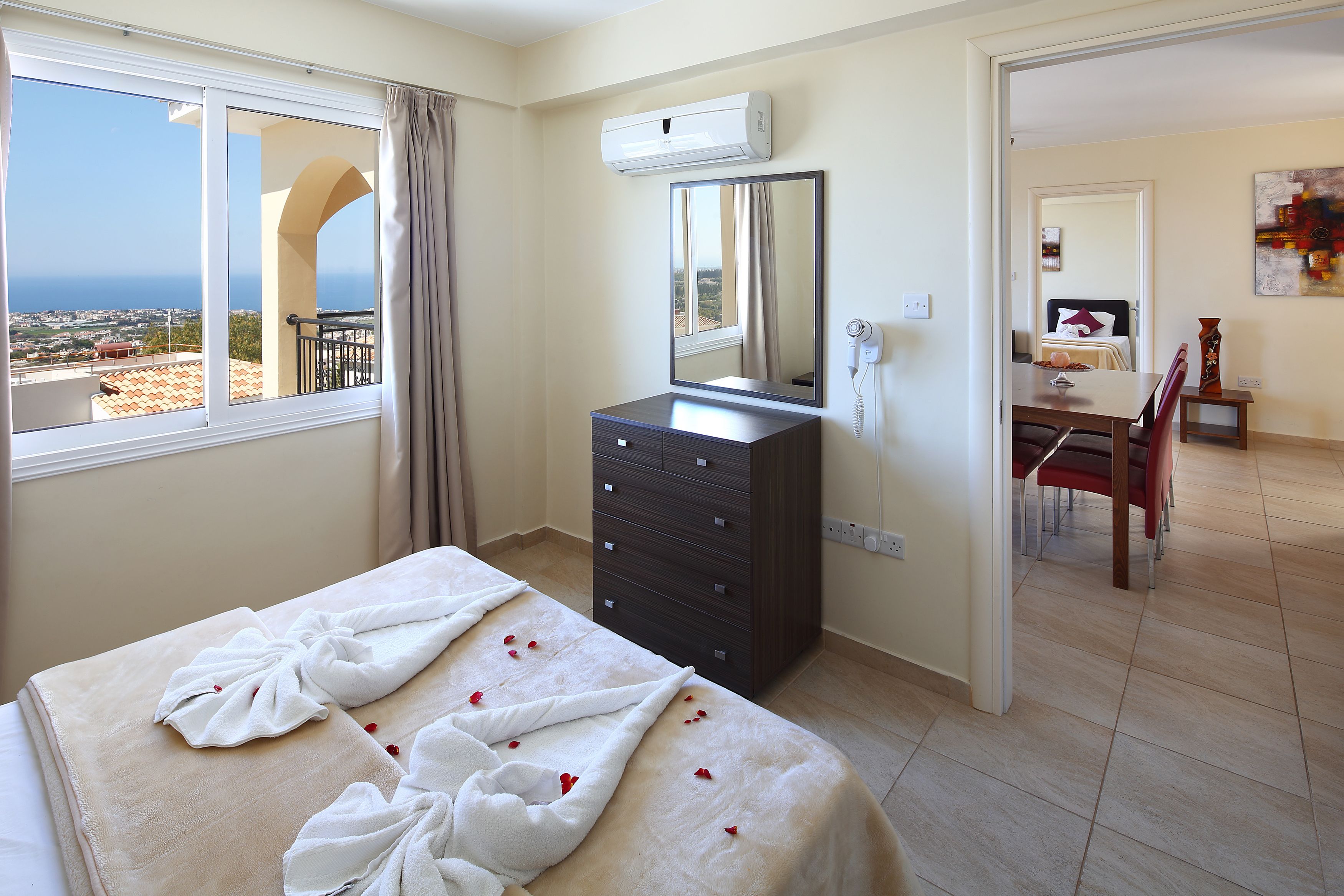 Una habitación de hotel con cama, cómoda, espejo y vista al mar.