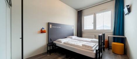 Een moderne hotelkamer met een bed, een bureau en een televisie.