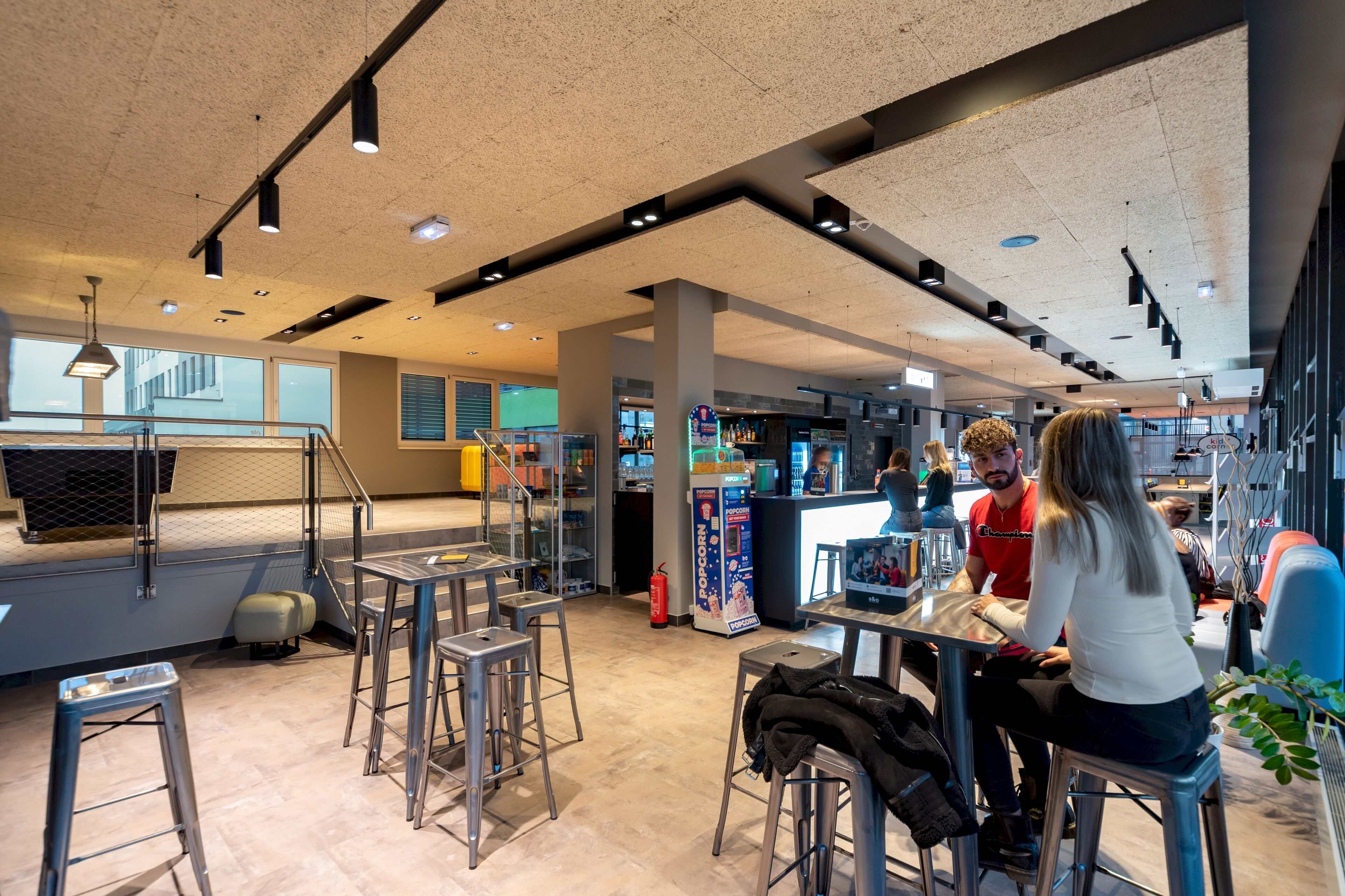 A modern interior with high ceilings, metal bar stools, and a central counter area.