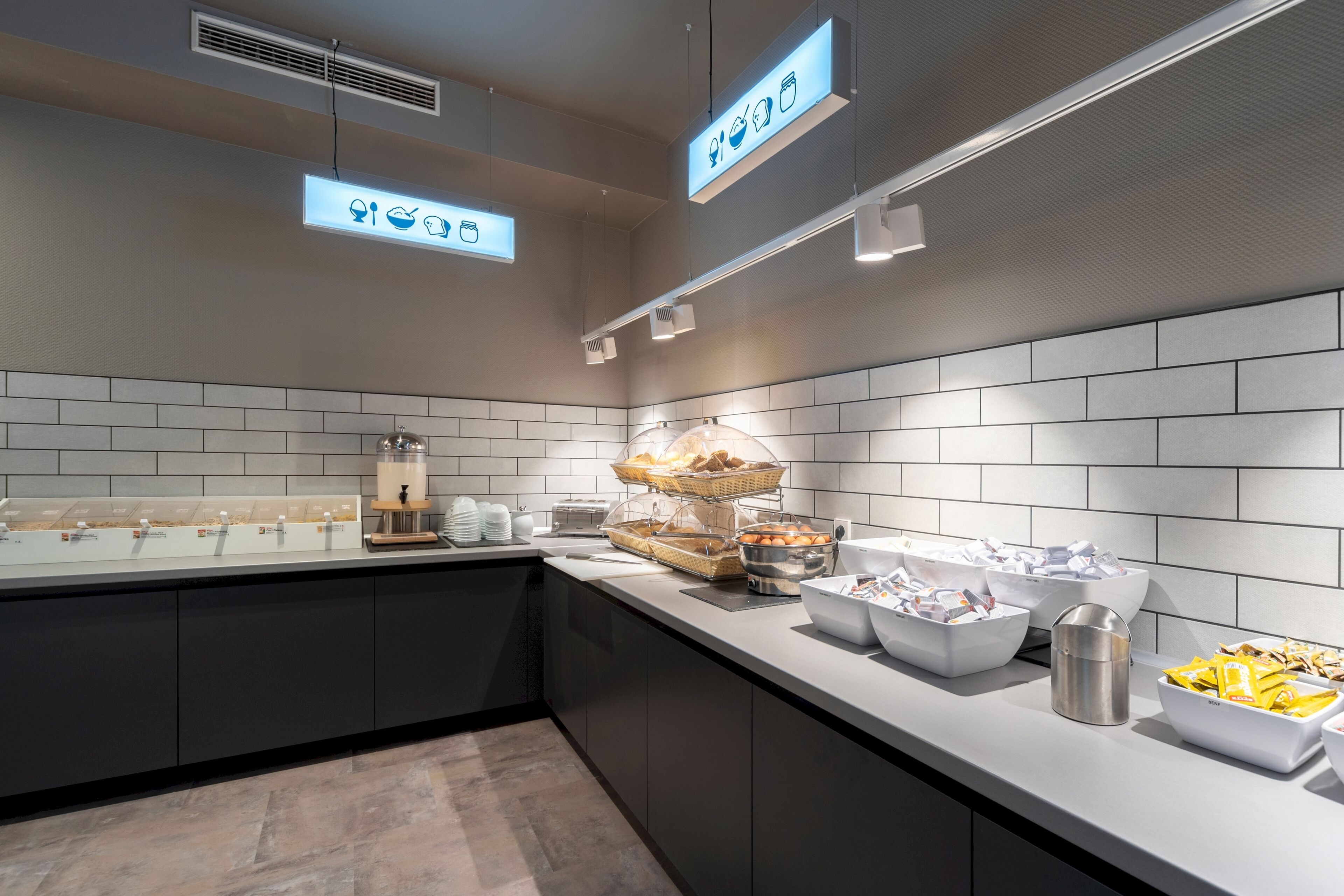 A modern kitchen with a buffet setup, including various food containers and a coffee machine.