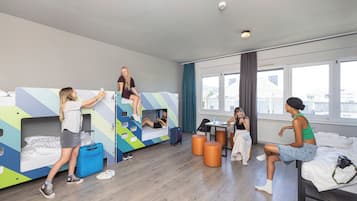 Ein modernes Schlafgemach einer Jugendherberge mit Stockbetten, einem Gemeinschaftstisch und einem großen Fenster.