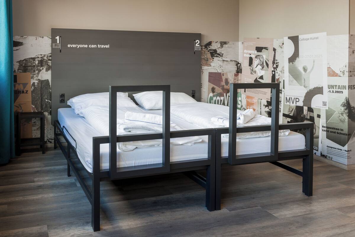 A modern bed with a grey headboard, white bedding, and a wooden floor.