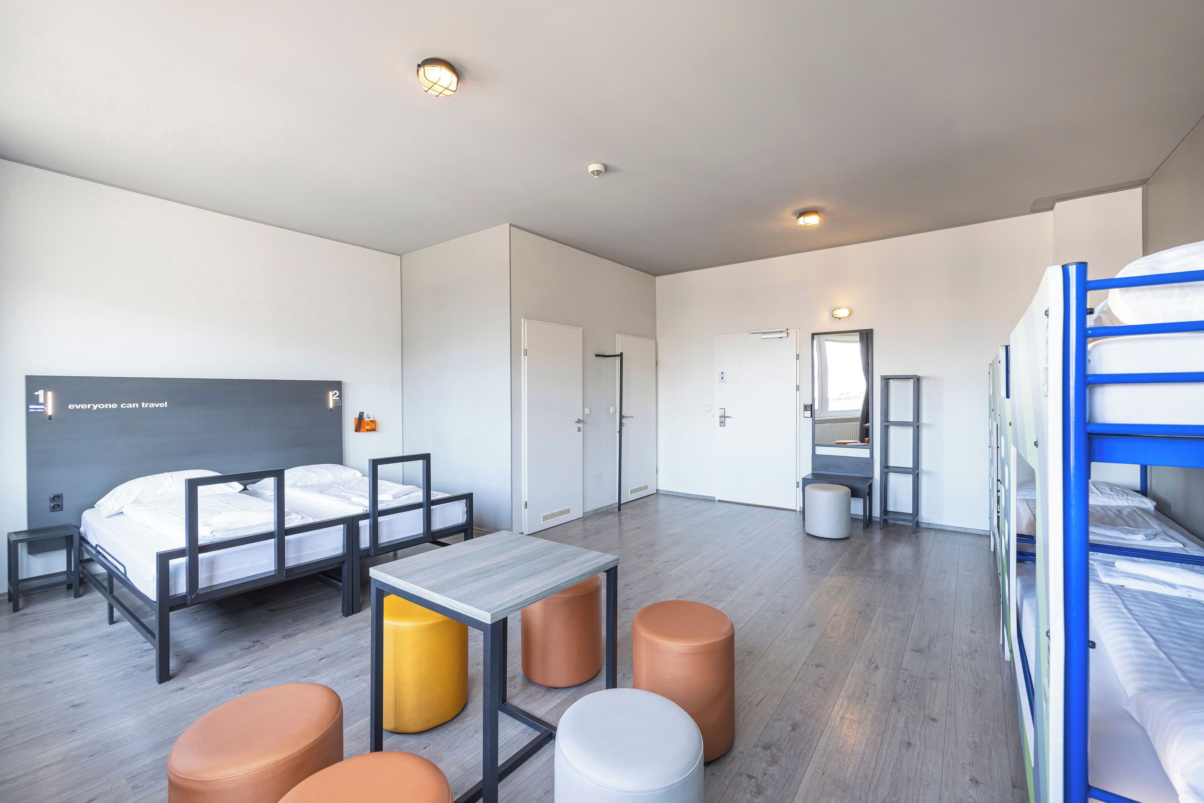 Ein modernes Hotelzimmer mit einem großen Bett, einem Schreibtisch und zwei Hocker.
