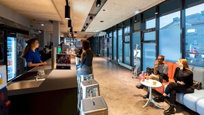Un bar moderno con un cantinero, asientos con vistas y una barra con dispensador de bebidas.