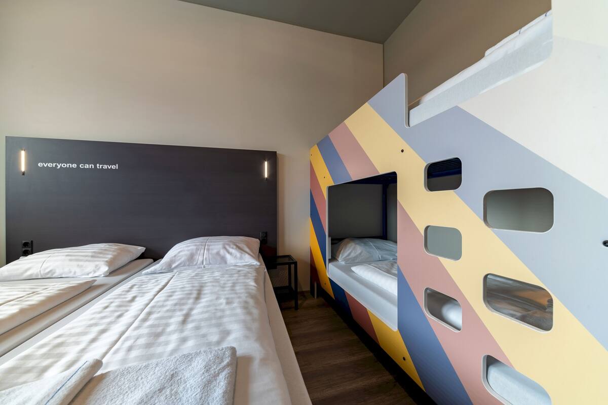 A hotel room with two beds, a colorful wall design, and a motivational quote on the headboard.
