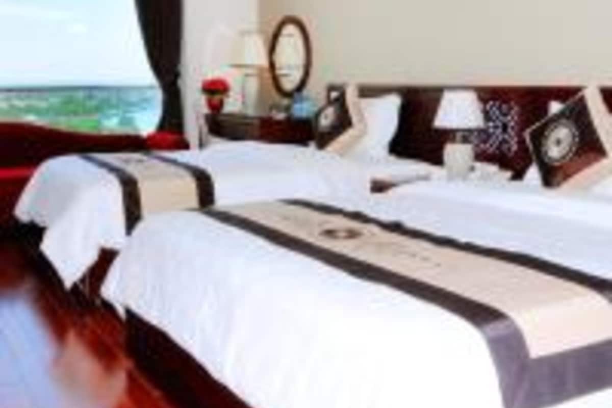 A hotel room with two beds, a large window, and a view of the sea.